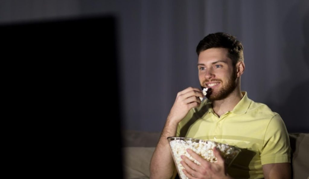 Un ragazzo mangia i pop corn davanti alla TV