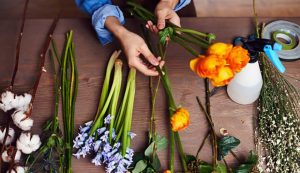 Persona con fiori su un tavolo da lavoro